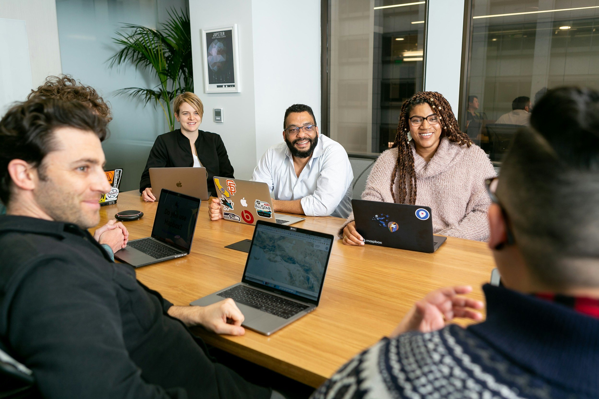 Diverse GTMVP team collaborating around conference table with laptops in modern office